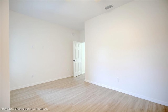 empty room with baseboards, visible vents, and light wood-type flooring