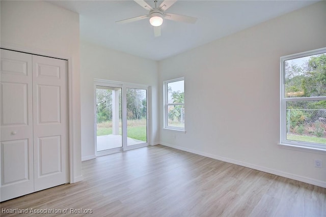 empty room featuring light wood-style floors, a healthy amount of sunlight, and baseboards