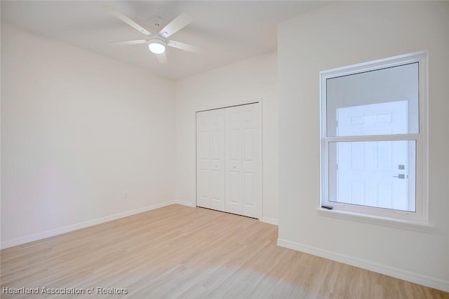 unfurnished bedroom with wood finished floors, baseboards, a closet, and ceiling fan