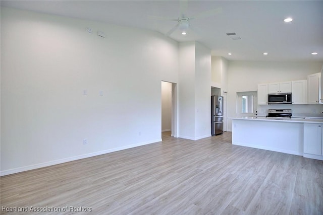 kitchen featuring light wood-style flooring, stainless steel appliances, light countertops, white cabinets, and open floor plan