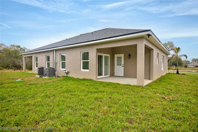 rear view of house featuring a yard, central AC unit, stucco siding, and a patio