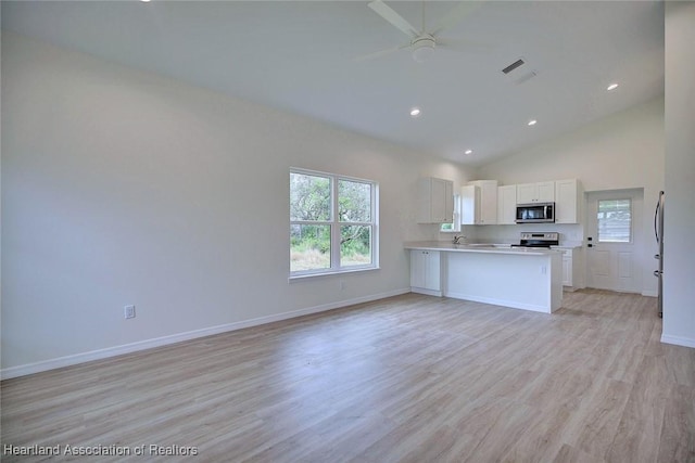 kitchen featuring light wood finished floors, baseboards, open floor plan, light countertops, and stainless steel appliances