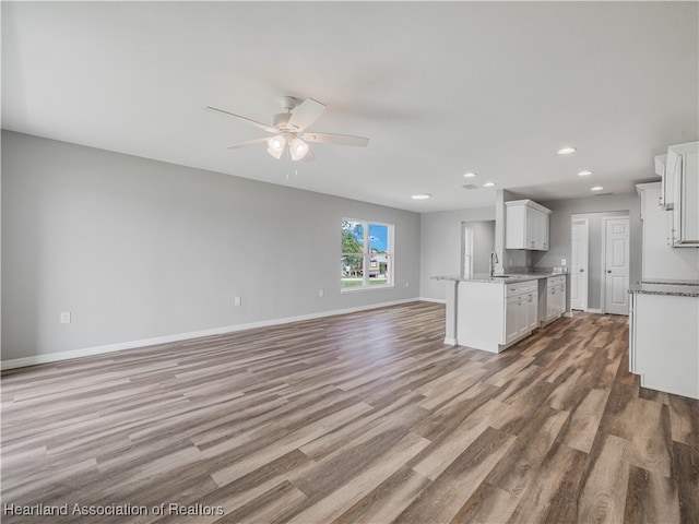 kitchen featuring sink, hardwood / wood-style flooring, ceiling fan, light stone counters, and white cabinetry