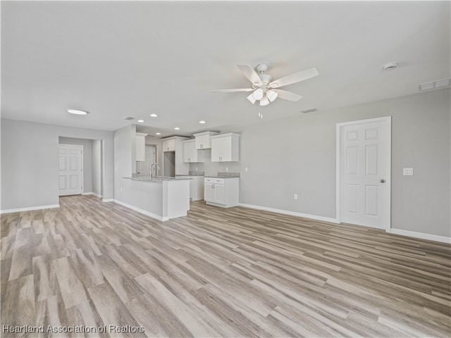 unfurnished living room featuring light wood-type flooring, ceiling fan, and sink