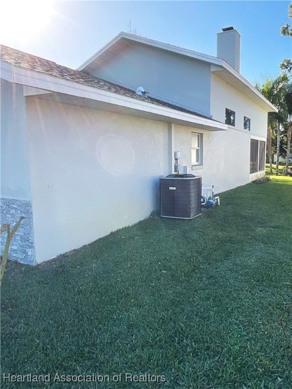 view of side of property featuring a yard and central AC