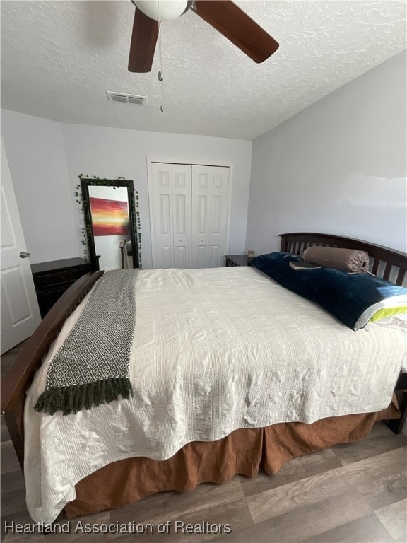 bedroom with ceiling fan, a closet, a textured ceiling, and hardwood / wood-style flooring