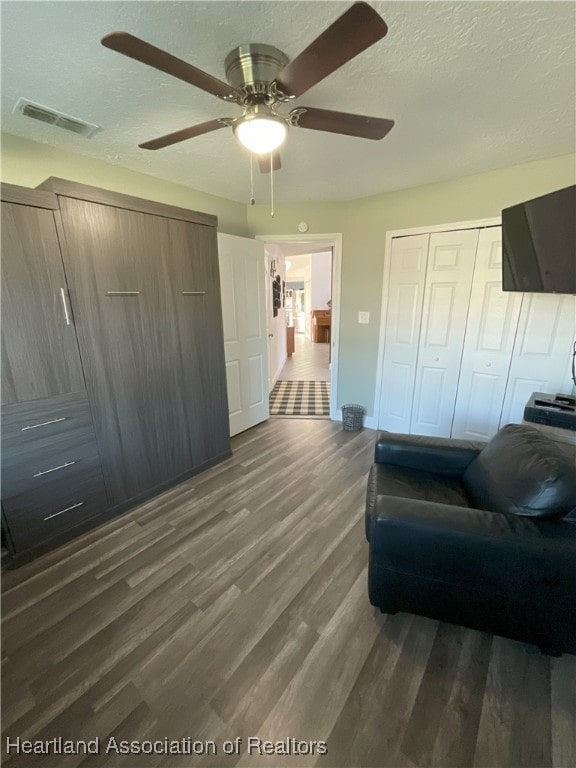 interior space featuring a textured ceiling, ceiling fan, and dark wood-type flooring