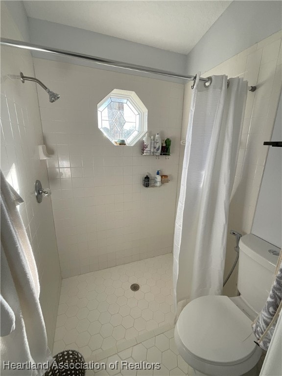 bathroom with a shower with shower curtain, tile patterned floors, and toilet