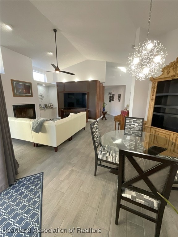 dining room with high vaulted ceiling, wood-type flooring, and ceiling fan with notable chandelier