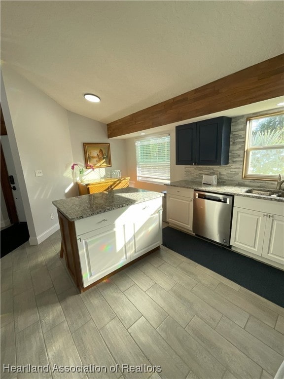 kitchen featuring white cabinets, sink, stainless steel dishwasher, decorative backsplash, and light stone counters