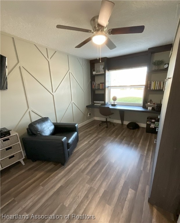 living area featuring ceiling fan, built in desk, and wood-type flooring