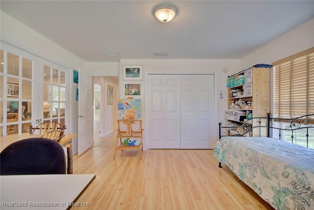 bedroom with hardwood / wood-style floors, french doors, and a closet