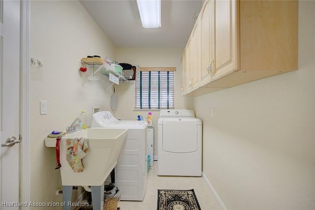 laundry area with cabinets, light tile patterned floors, sink, and washing machine and clothes dryer