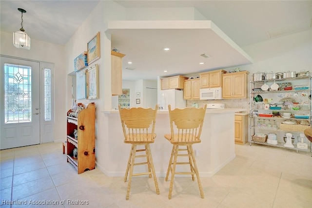 kitchen featuring light brown cabinets, kitchen peninsula, white appliances, a breakfast bar area, and light tile patterned floors