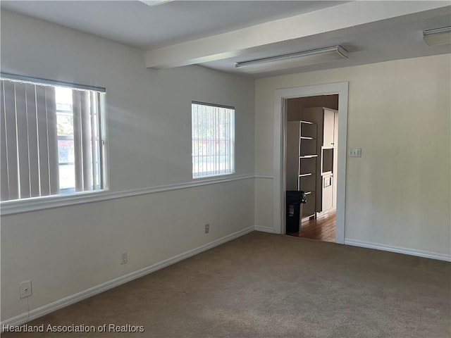 unfurnished bedroom with beamed ceiling and dark carpet