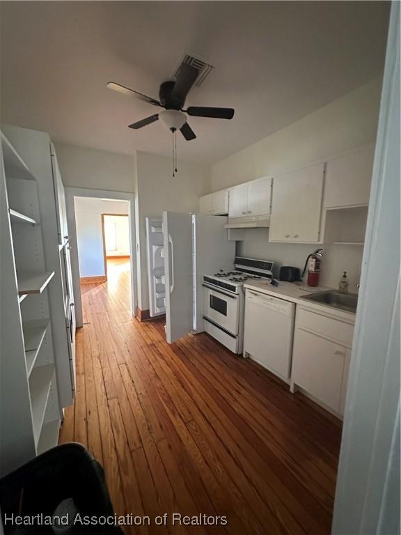 kitchen featuring white appliances, wood-type flooring, sink, ceiling fan, and white cabinetry