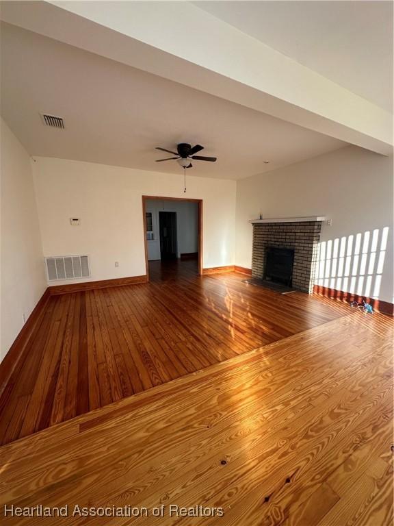 unfurnished living room featuring hardwood / wood-style floors, ceiling fan, and a fireplace