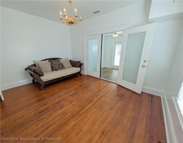 unfurnished room with hardwood / wood-style flooring, a notable chandelier, and french doors