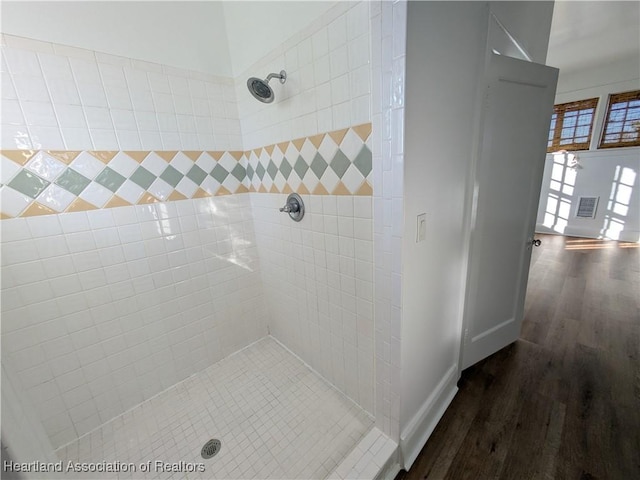 bathroom with hardwood / wood-style floors and a tile shower