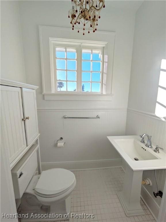 bathroom featuring a chandelier, tile patterned floors, and toilet