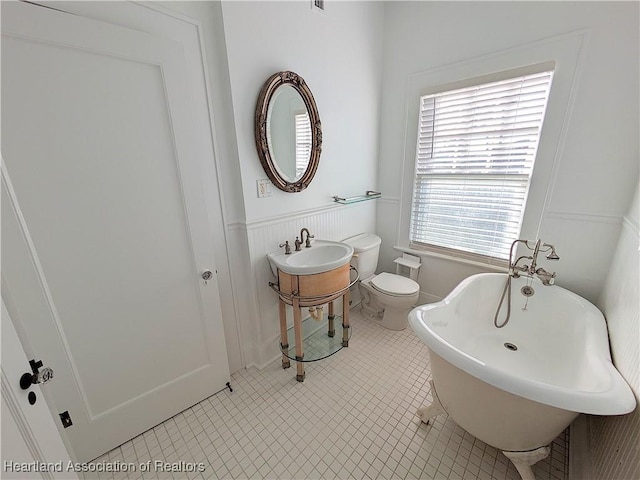 bathroom featuring a washtub, tile patterned floors, and toilet