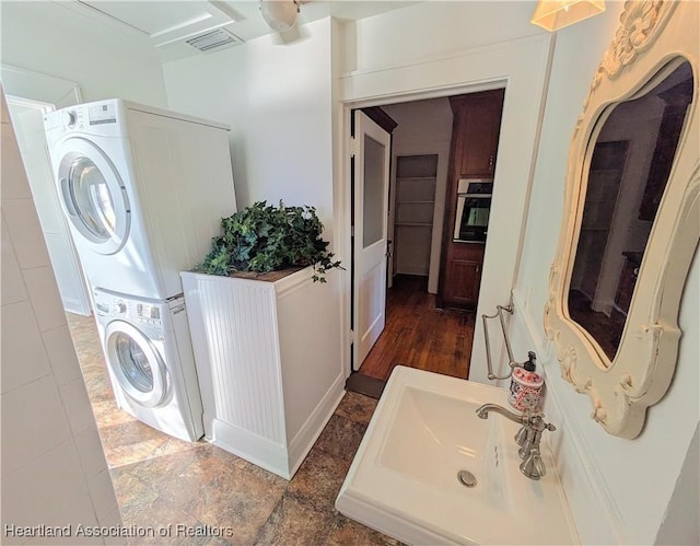 laundry area featuring stacked washer / dryer and sink