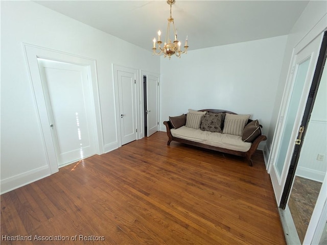 living area with dark wood-type flooring and a notable chandelier