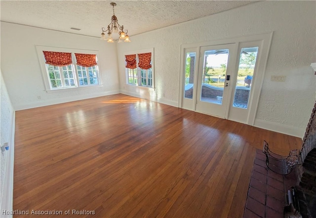 empty room with a chandelier, a textured ceiling, and hardwood / wood-style flooring