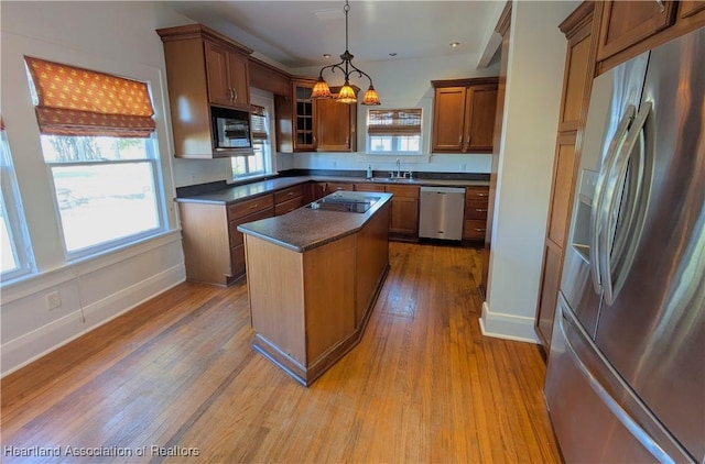 kitchen featuring sink, black appliances, pendant lighting, a center island, and light hardwood / wood-style floors