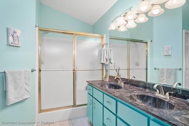 bathroom featuring tile patterned flooring, vanity, vaulted ceiling, and a shower with door