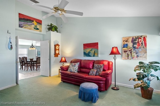 carpeted living room featuring vaulted ceiling and ceiling fan with notable chandelier