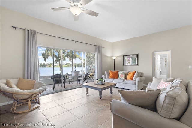 living room with a water view, light tile patterned floors, baseboards, and ceiling fan