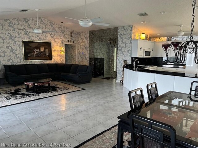 tiled dining space with ceiling fan, sink, and lofted ceiling