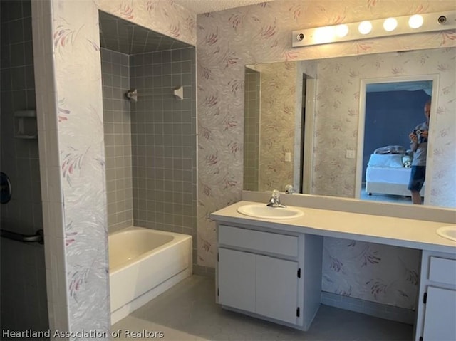 bathroom featuring vanity, a textured ceiling, and tiled shower / bath combo