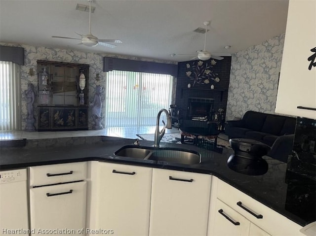 kitchen with a fireplace, white cabinets, white dishwasher, and sink