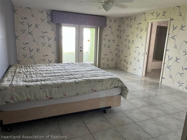 bedroom featuring ceiling fan, light tile patterned floors, ensuite bathroom, and a textured ceiling