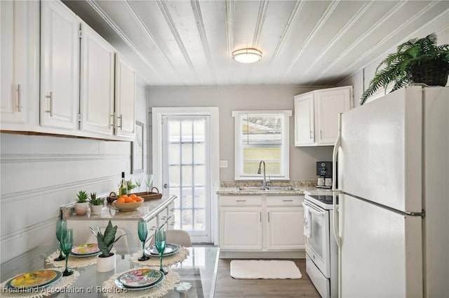 kitchen featuring white cabinetry, sink, light stone countertops, and white appliances