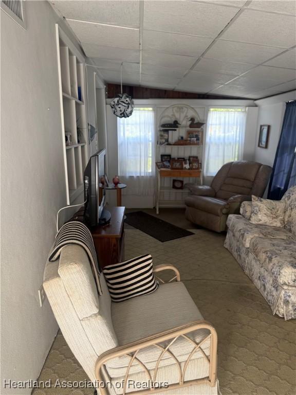 living area with visible vents, a healthy amount of sunlight, and a paneled ceiling