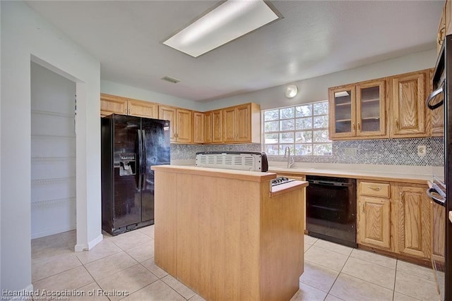 kitchen featuring backsplash, sink, black appliances, light tile patterned floors, and a kitchen island