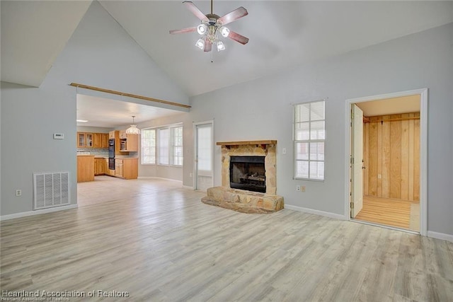 unfurnished living room with a fireplace, light wood-type flooring, high vaulted ceiling, and ceiling fan