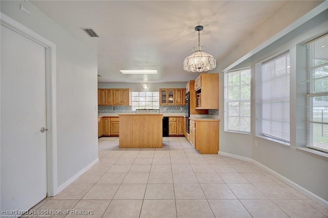 kitchen with light tile patterned floors, backsplash, pendant lighting, a chandelier, and a kitchen island