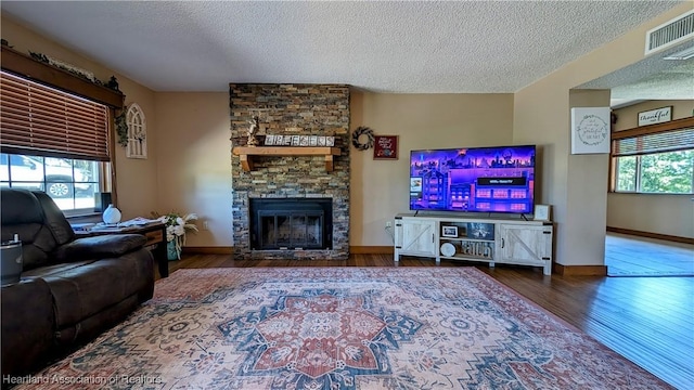 living room with a textured ceiling, plenty of natural light, a fireplace, and hardwood / wood-style flooring