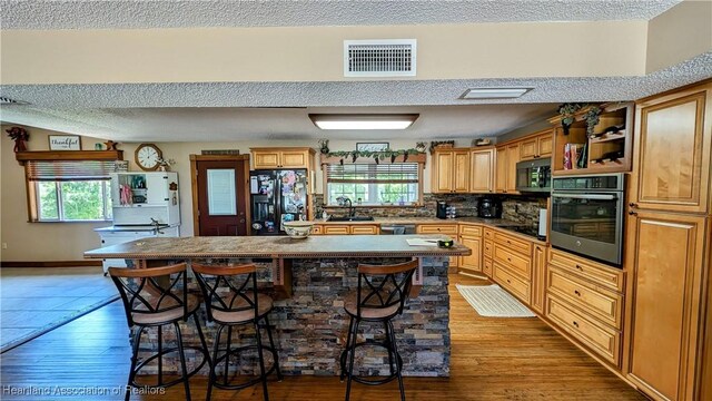 3214 Whipporwill Ln, Wauchula, FL 33873 - kitchen featuring light wood-type flooring, a breakfast bar, sink, black appliances, and a kitchen island