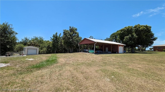 view of yard featuring a carport, an outdoor structure, and a garage