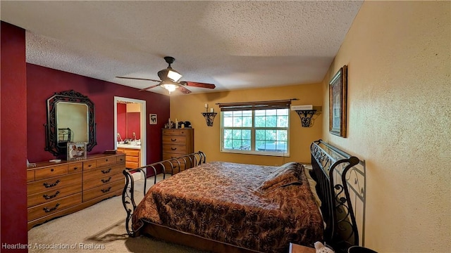 carpeted bedroom featuring a textured ceiling, ensuite bath, and ceiling fan