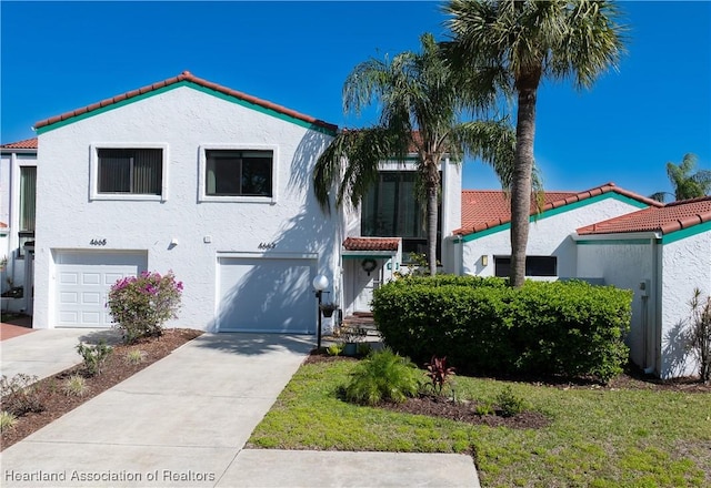 mediterranean / spanish-style house with a garage, driveway, and stucco siding