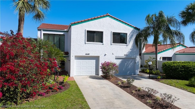 mediterranean / spanish-style home with a garage, concrete driveway, a tile roof, and stucco siding