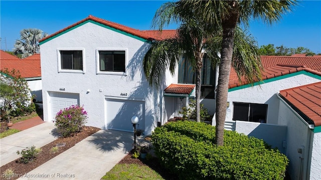 view of front of property featuring a garage, a tiled roof, and stucco siding