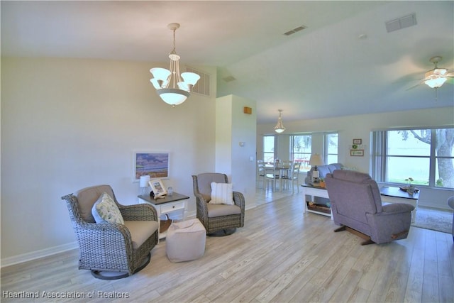 living area with lofted ceiling, light wood-style flooring, and visible vents