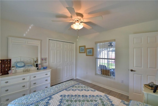 bedroom with a ceiling fan, a closet, light wood-style flooring, and baseboards